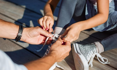 Hände binden die Schuhe eines Kindes Hände binden die Schuhe eines Kindes